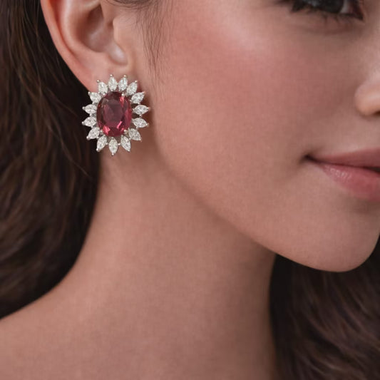 Ruby color stone stud earrings with diamond halo design worn on ear