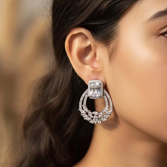 Silver diamond emerald cut halo drop earrings worn by a woman, elegant sterling silver jewellery
